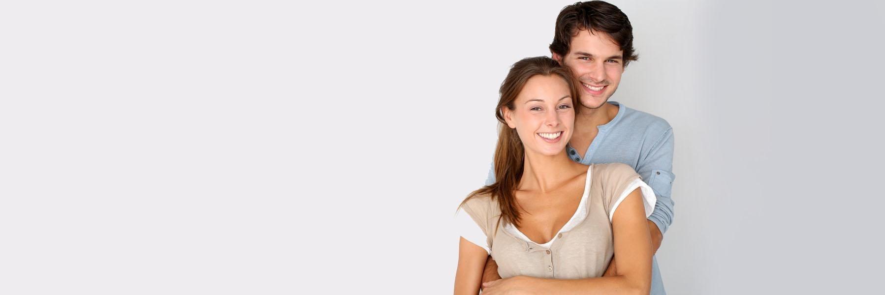 Young couple holding each other & smiling after family dentistry at Jerger Pediatric Dentistry