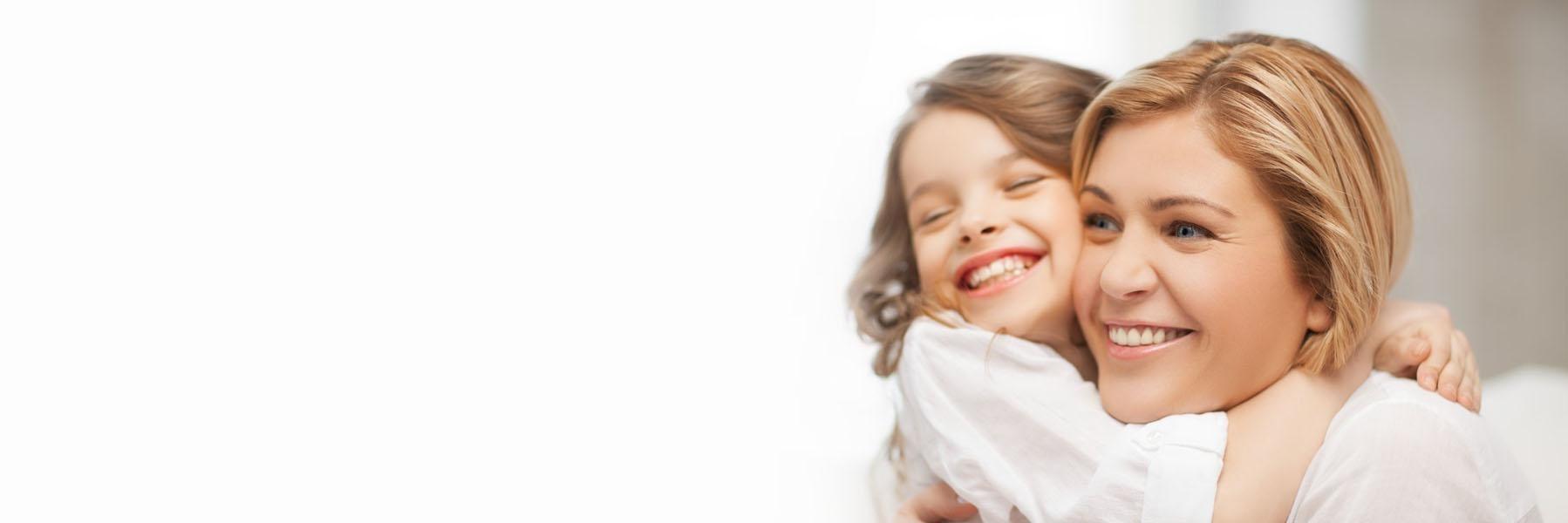Woman & girl hugging & smiling after brushing teeth in Decatur, IL