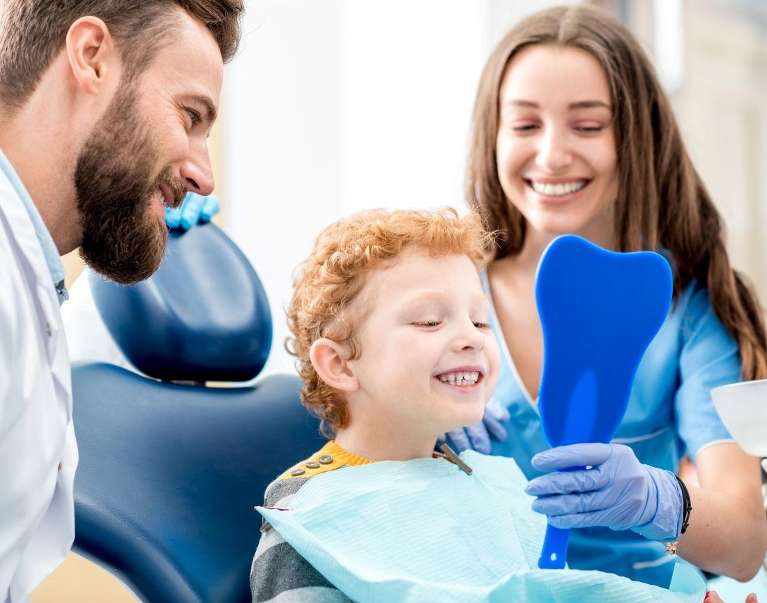 Two dentist smiling and showing a kids his new Braces in Decatur, IL